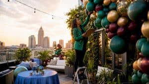 Event planner adjusting hanging floral decor overhead