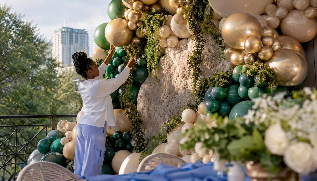 Elegant Birthday Party Decor Explained: Your 2026 Style Guide Event stylist crafting upscale balloon arch indoors